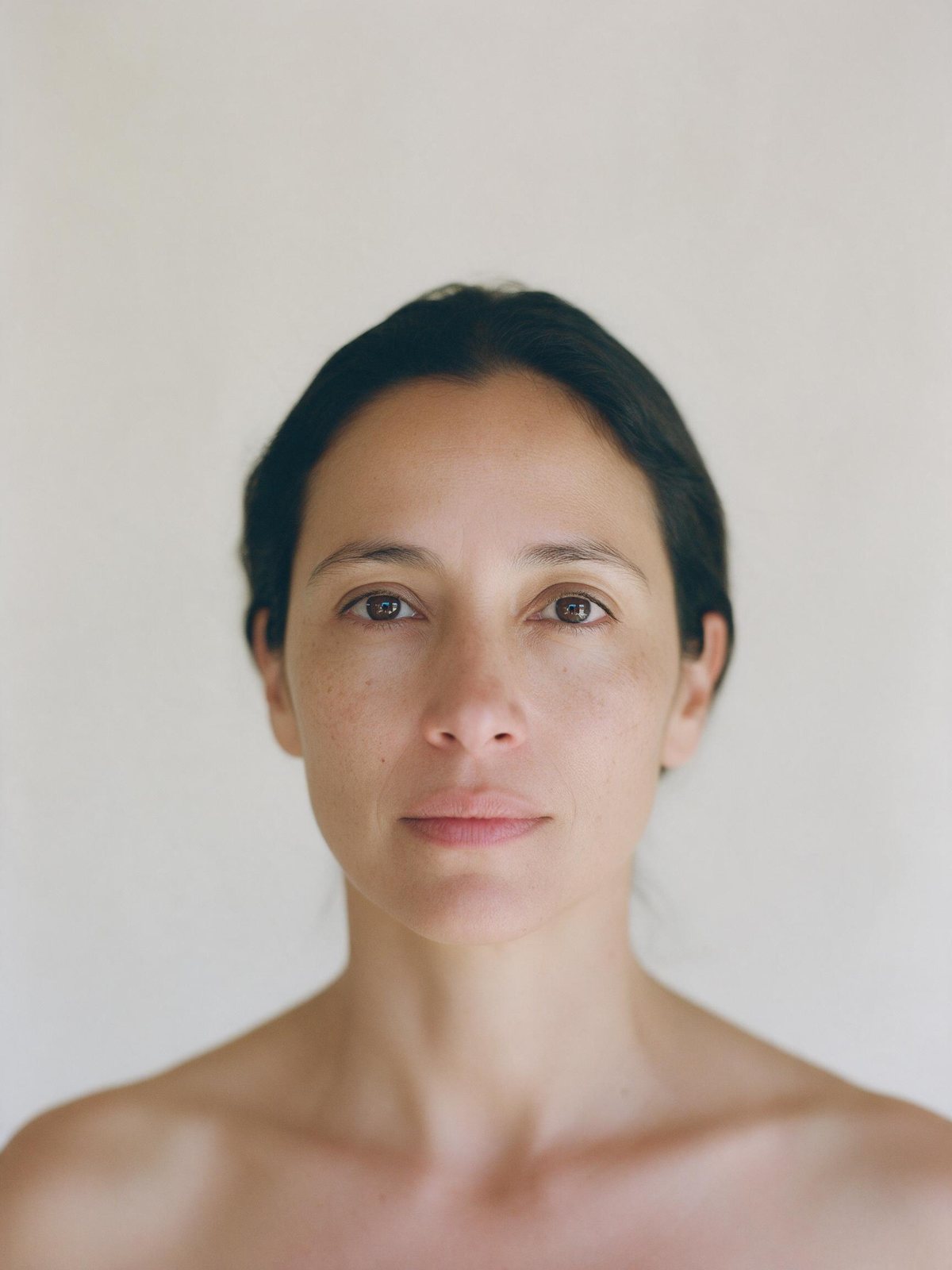 Retrato de frente, sin maquillaje, con tres marcas de medición sobre el rostro.
